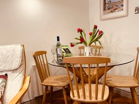 A glass dining table with wooden chairs red flowers in a vase a bottle of wine and a glass at 7 Watkin Street in Conwy