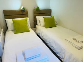 A bedroom with two single beds with green cushions and folded towels at 7 Watkin Street in Conwy
