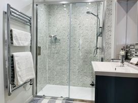 A bathroom with a glass shower enclosure towel rack with towels and a sink at 7 Watkin Street in Conwy