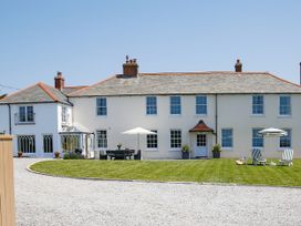 A house with patio chairs and umbrellas at Porthcothan House in St Merryn