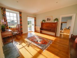 A living room with a bench and a desk at Porthcothan House in St Merryn