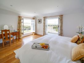 A bedroom with a bed, table, and window at Porthcothan House in St Merryn