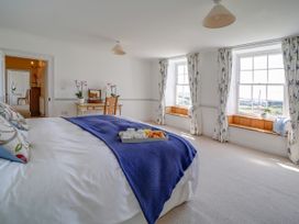 A bedroom with a bed and a table at Porthcothan House in St Merryn