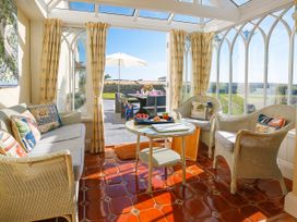 A conservatory with seating and a table at Porthcothan House in Porthcothan