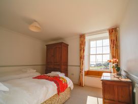 A bedroom with two beds and a wardrobe at Porthcothan House in Porthcothan