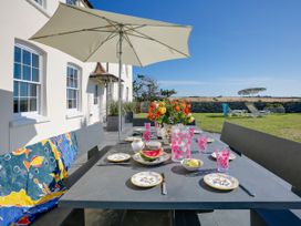 An outdoor dining setup with a table and chairs at Porthcothan House in Porthcothan