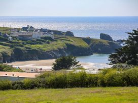 A view of a beach with houses on cliffs at Porthcothan House in Porthcothan