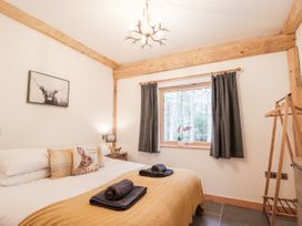 A bedroom with a bed with pillows and towels a window with curtains and a wooden clothes rack at Pine Marten Lodge in Dulnain Bridge near Nethy Bridge