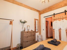 A bedroom with a wooden chest of drawers a clothing rack a mirror and two white bathrobes hanging on a wooden door at Pine Marten Lodge Dulnain Bridge near Nethy Bridge