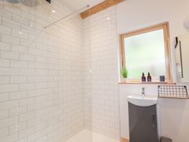 A bathroom with a walk-in shower white tiled walls a window and a sink cabinet at Pine Marten Lodge Dulnain Bridge near Nethy Bridge