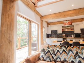 A living room with a patterned throw on the sofa next to large glass doors opening to a wooden balcony at Pine Marten Lodge in Dulnain Bridge near Nethy Bridge