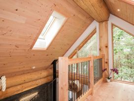 An upper level wooden balcony with railings and large windows overlooking trees at Pine Marten Lodge Dulnain Bridge near Nethy Bridge