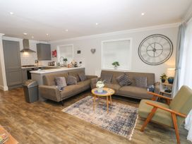 A living room with two sofas a chair a round table and a large clock on the wall at Rookley Lake Cottage in Rookley near Godshill