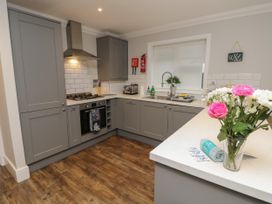 A kitchen with grey cabinets a gas stove a sink and flowers on the counter at Rookley Lake Cottage in Rookley near Godshill