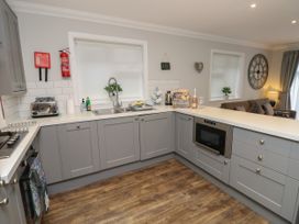 A kitchen with grey cabinets wooden floor toaster and oven at Rookley Lake Cottage in Rookley near Godshill
