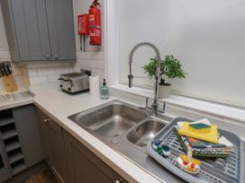 A kitchen sink with a flexible faucet soap dispenser and cleaning items on the counter next to a window at Rookley Lake Cottage in Rookley near Godshill