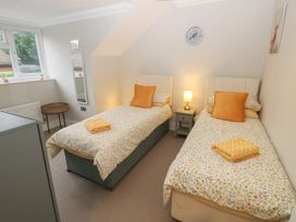 A bedroom with two single beds a nightstand with a lamp and a wall clock at Rookley Lake Cottage in Rookley near Godshill