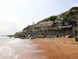 A beachfront inn with flags and a rocky shoreline at Spyglass Inn