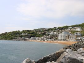 A coastal town with buildings on a hillside overlooking a beach and rocky shoreline at Rookley Lake Cottage in Rookley near Godshill
