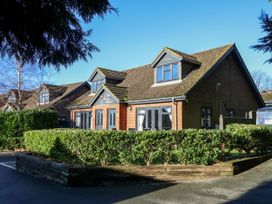 A residential building with brick walls and a tiled roof surrounded by trimmed hedges at Rookley Lake Cottage in Rookley near Godshill