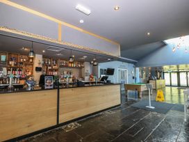 A bar area with wooden counters and taps next to a pool table and entrance doors at Rookley Lake Cottage Rookley near Godshill