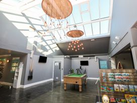 A recreational room with a pool table under hanging lights and a skylight at Rookley Lake Cottage in Rookley near Godshill