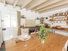 A kitchen with a wooden table and utensils on a shelf at Sycamore Vestry in Pontfaen near Fishguard