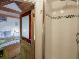 A bathroom with a shower and a wooden door at Sycamore Vestry in Pontfaen near Fishguard
