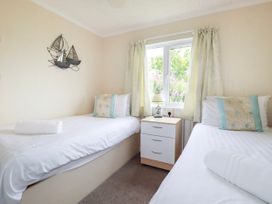 A bedroom with two beds and a bedside table at Chi Prenn Byhan in Tintagel