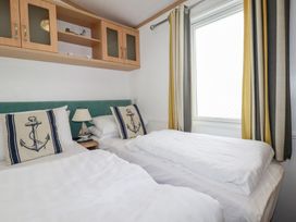 A bedroom with two beds and a window at Orchard View in Bossiney near Tintagel