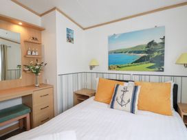 A bedroom with a bed and mirror at Orchard View in Bossiney near Tintagel