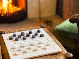 A checkerboard with black and white pieces next to a fireplace at The Captain's Nest in Bunbeg, County Donegal