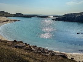 A beach with water and rocks at The Captain's Nest in Bunbeg, County Donegal