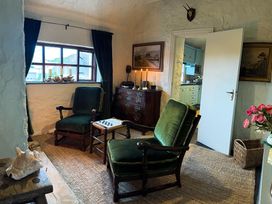 A living room with green armchairs and a table at The Captain's Nest in Bunbeg, County Donegal