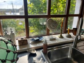 A kitchen window with various items including soap bottles and candles at The Captain's Nest in Bunbeg, County Donegal