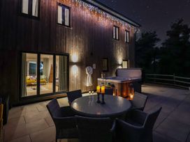 An outdoor area with a dining table and hot tub at Stag Cottage in Lytchett Matravers