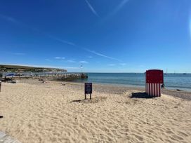 A beach with a pier and a beach hut at The Barn in Lytchett Matravers