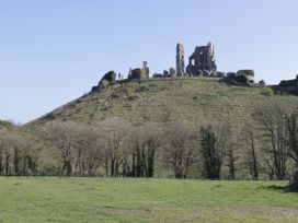 Castle ruins on a hill with trees and grass in the foreground at The Barn in Lytchett Matravers
