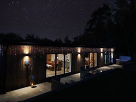 An exterior view of a house at night with lights and a Christmas tree at The Barn in Lytchett Matravers