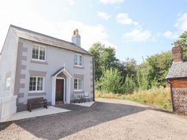 A house with a gravel driveway and bench at Burgedin Locks Cottage Arddleen near Llandrinio