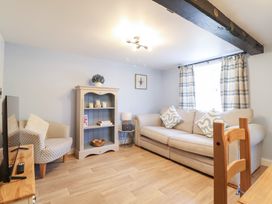 A living room with a sofa and bookshelf at Burgedin Locks Cottage Arddleen near Llandrinio