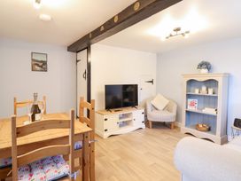 A living room with a TV and dining area at Burgedin Locks Cottage in Arddleen near Llandrinio