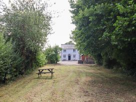 An outdoor area with a house and a bench at Burgedin Locks Cottage Arddleen near Llandrinio