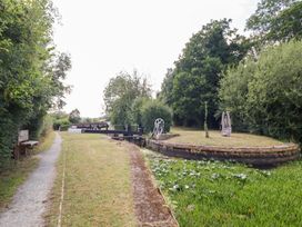 A pathway near a water lock with benches and surrounding trees at Burgedin Locks Cottage Arddleen near Llandrinio