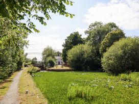A pathway beside a green area with trees at Burgedin Locks Cottage Arddleen near Llandrinio