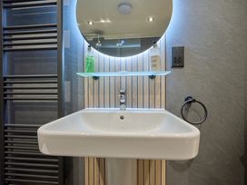 A wash basin with a mirror and shelf at Riverside Park 1 in Keswick