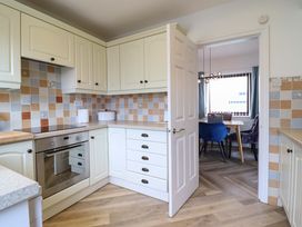 A kitchen with white cabinets and a doorway to a dining area at Ser a Mor (Stars and Sea) Bull Bay near Amlwch