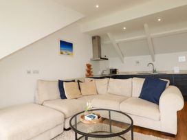 A living room with a sofa and kitchen counter at 5 St Gwithian Apartments in 