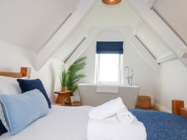 A bedroom with a bathtub and plant at 5 St Gwithian Apartments