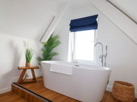 A bathroom with a bathtub and plant at 5 St Gwithian Apartments